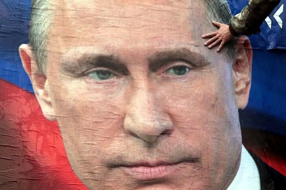 Un hombre pega un cartel del Presidente de Rusia, Vladimir Putin, en Crimea.