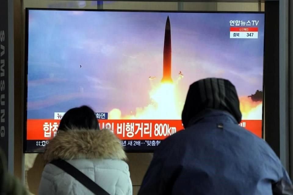 La gente mira un televisor que muestra una imagen de archivo del lanzamiento de un misil de Corea del Norte durante un programa de noticias en la estación de tren de Seúl.