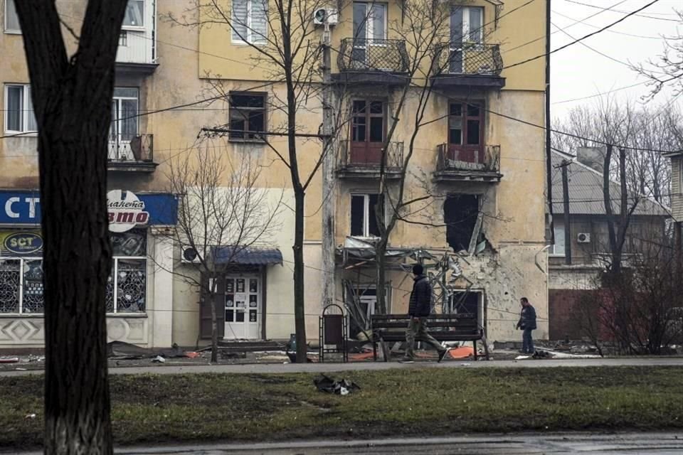 Un hombre camina en la ciudad de Mariúpol junto a un edificio dañado por los bombardeos.