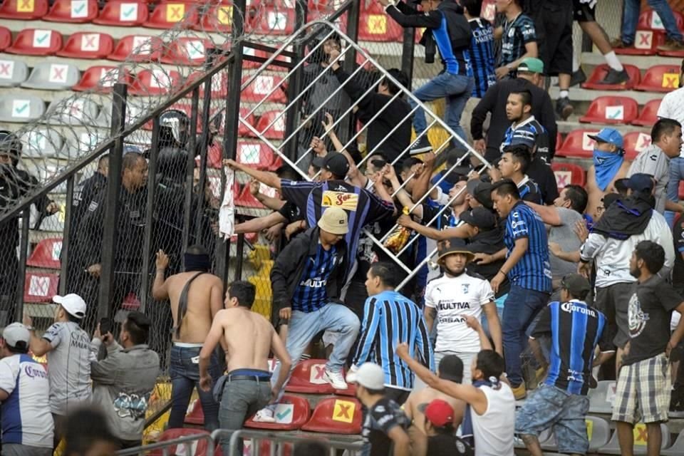 Hinchas queretanos tratando de pasar el enrejado para atacar a los rojinegros.