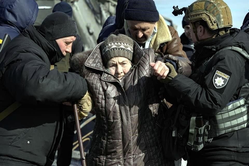 Policías ucranianos ayudan a una persona mayor a evacuar la ciudad de Irpin.