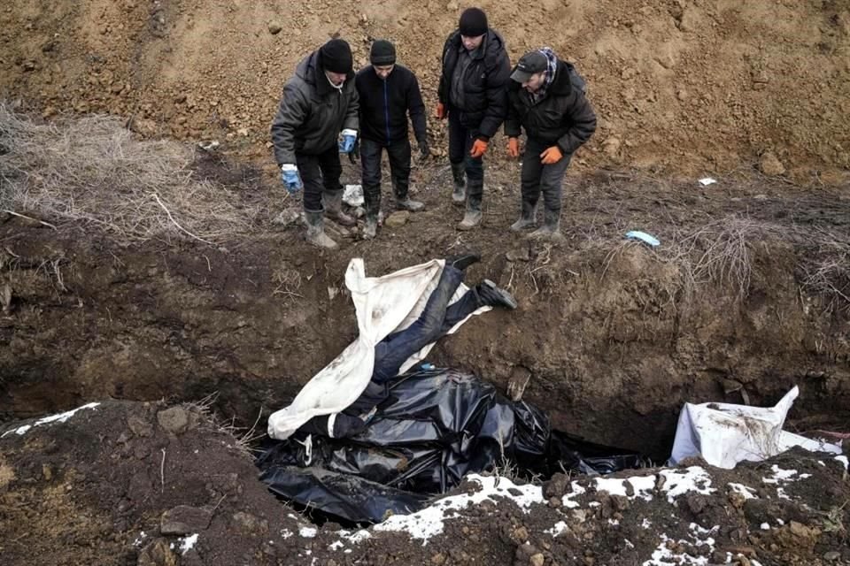 Un cuerpo es arrojado a una fosa común en Mariúpol.