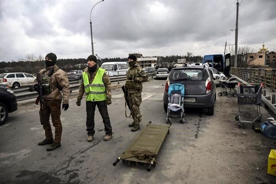 Soldados ucranianos vigilan un puente dañado de Irpin que ha sido usado para evacuar a los residentes.