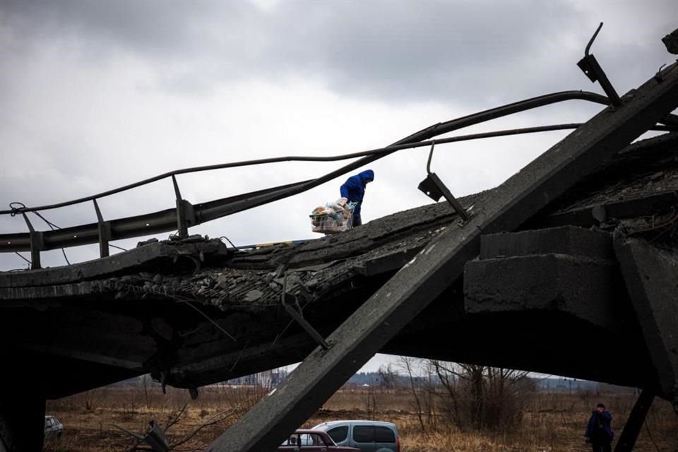 Un voluntario empuja una carretilla por un puente destruido, en Irpin.