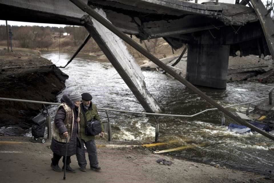 Dos ancianos caminan por un puente destruido para evacuar Irpin.