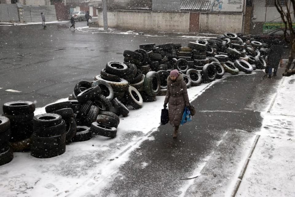 Una mujer camina junto a una barricada de llantas en Mykolaiv, Ucrania.