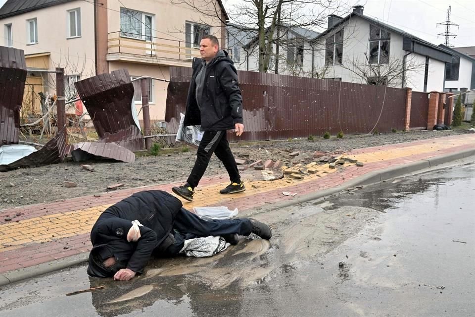Un hombre camina junto a un cadáver aparentemente civil en las afueras de Kiev.