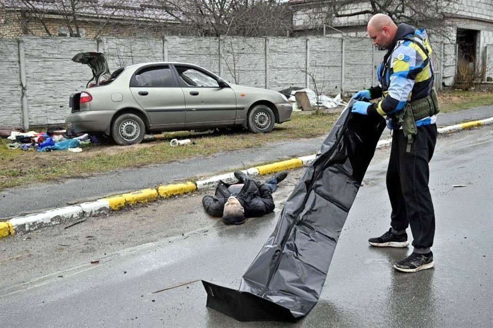 Un trabajador en Bucha se prepara para meter a una bolsa un cadáver de una persona fallecida.