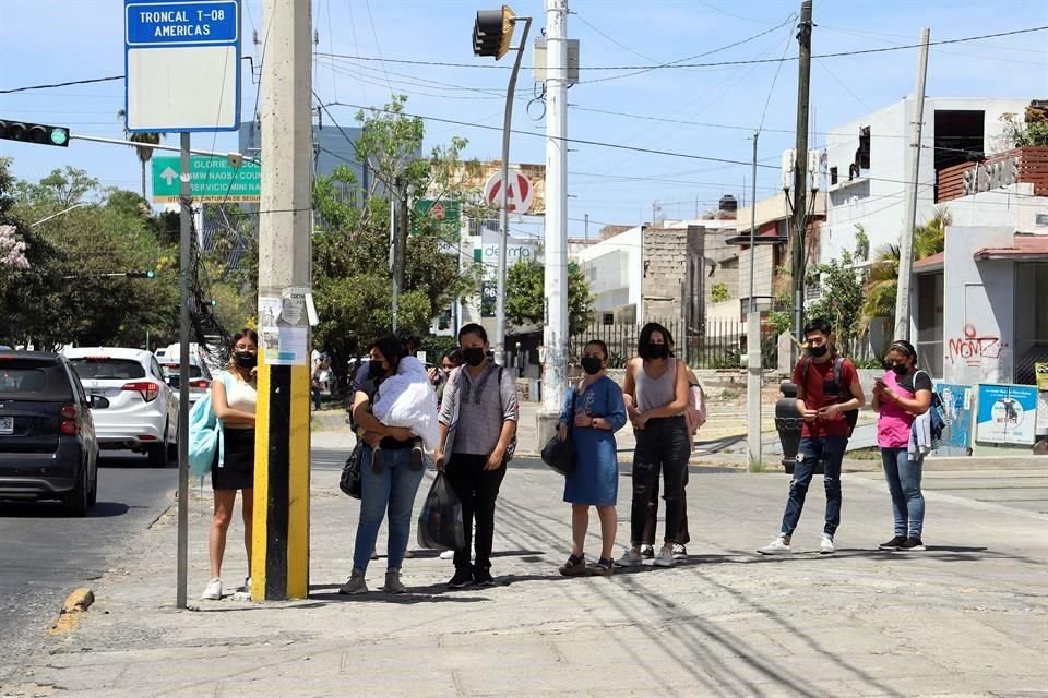 Usuarios de transporte público esperando el camión en la sombra de un poste de luz, en la esquina de Américas y Manuel Acuña.