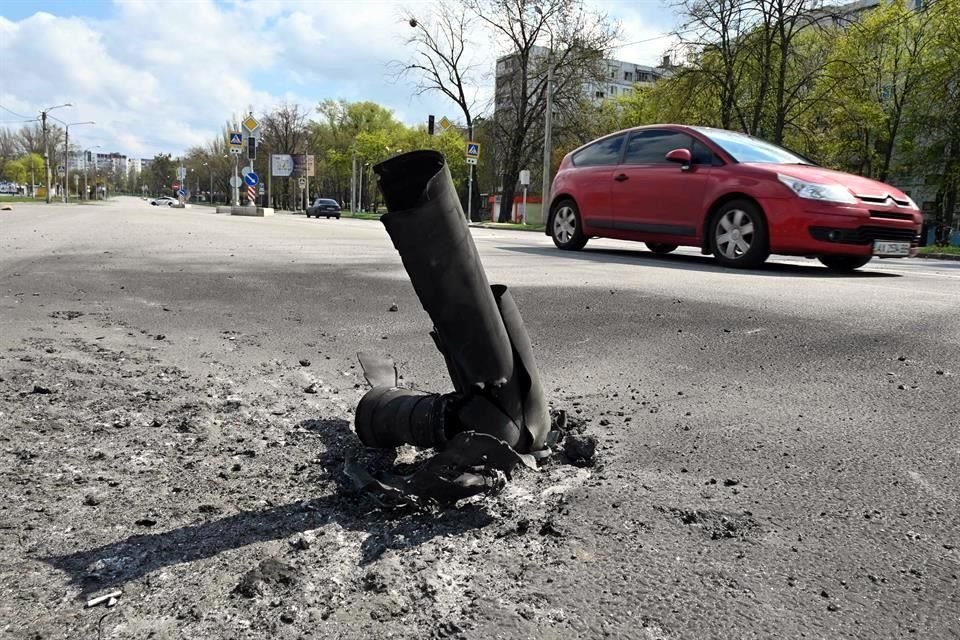 Un auto pasa por los residuos de un misil en un área residencial tras un bombardeo en las afueras de Járkov.