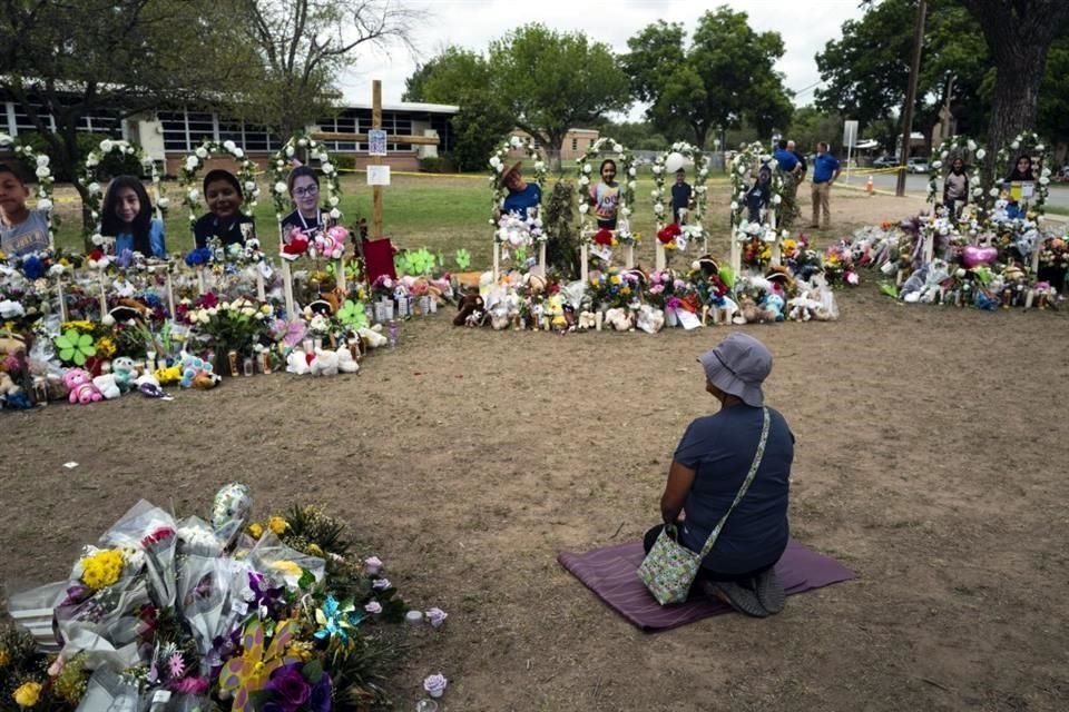 Una mujer se arrodilla frente al memorial de las víctimas del tiroteo en la escuela Primaria Robb.