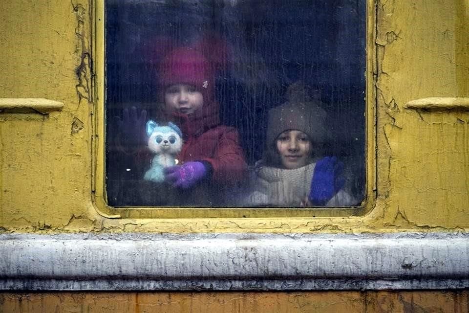 Niños miran por la ventana de un tren sin calefacción con destino a Lviv, en Kiev, Ucrania.