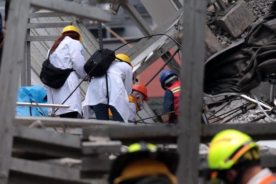 Las dos mujeres peritos, identificadas por las batas blancas que portan, recorren el lugar tomando fotografías y colocando marcadores en lugares importantes.