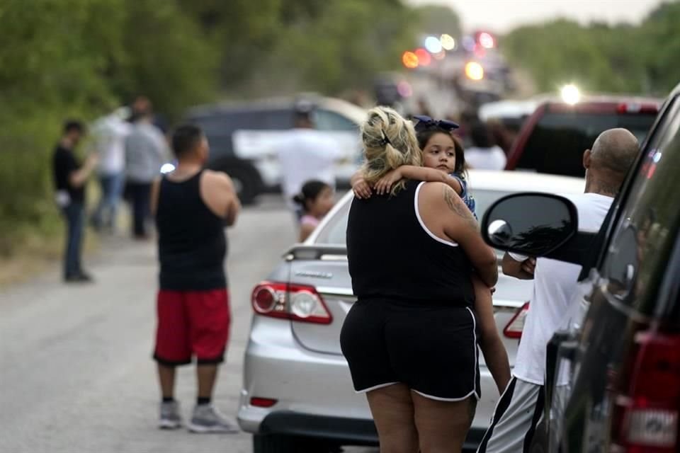 Personas miran cerca de la escena donde se halló el tráiler abandonado con cuerpos de migrantes.