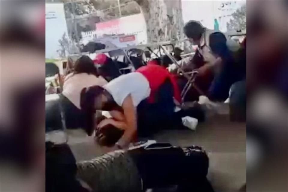 Una madre cubre a su hijo mientras se desata una balacera en la fila de vacunación anti-Covid en la capital de Puebla.