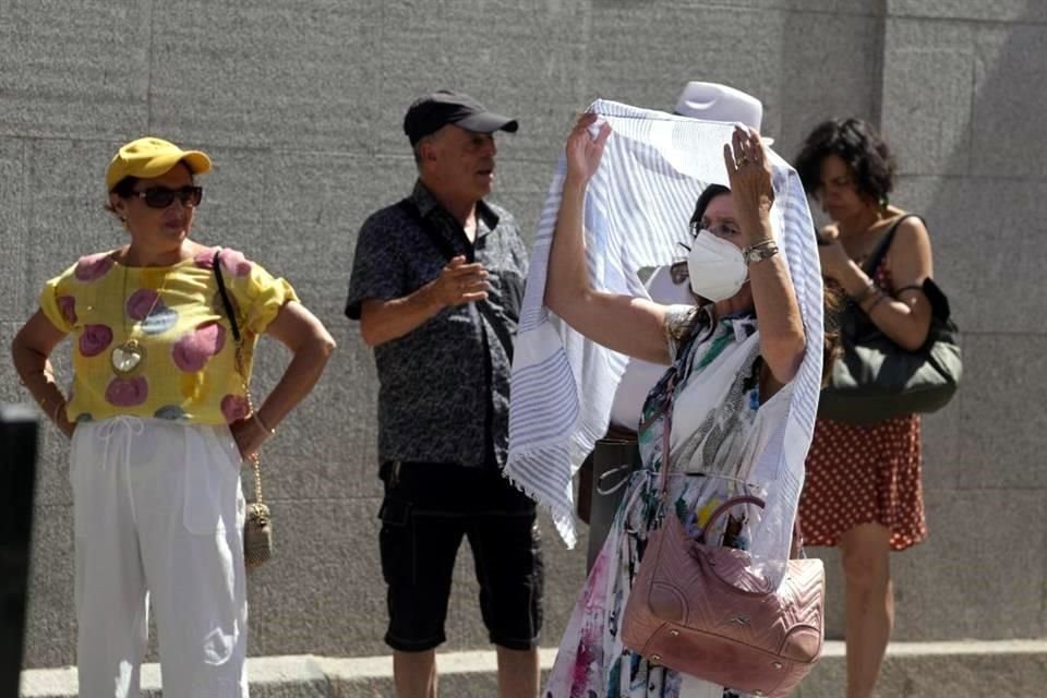Una mujer hace fila frente al teatro de la Ópera para protegerse del sol durante el clima cálido en Madrid, España.