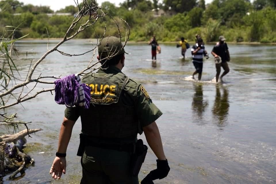 Un agente de la Patrulla Fronteriza observa a un grupo de migrantes cruzar el Rio Grande en su camino para entregarse a las autoridades de EU, en Del Rio, Texas.