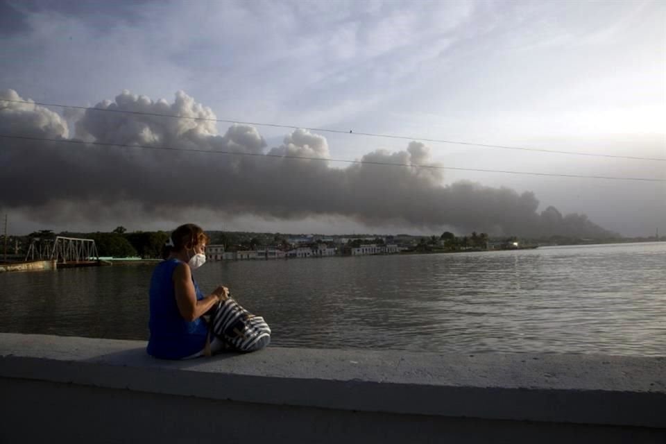 Una residente se sienta en el malecón de Matanzas, mientras observa un humo menos denso que los días anteriores.