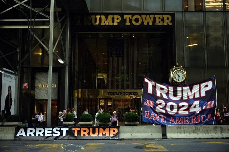 Opositores a Trump desplegaron una manta que pide su arresto frente a su torre en Nueva York, mientras que simpatizantes llevaron otra que lo alienta a competir por la Presidencia nuevamente.