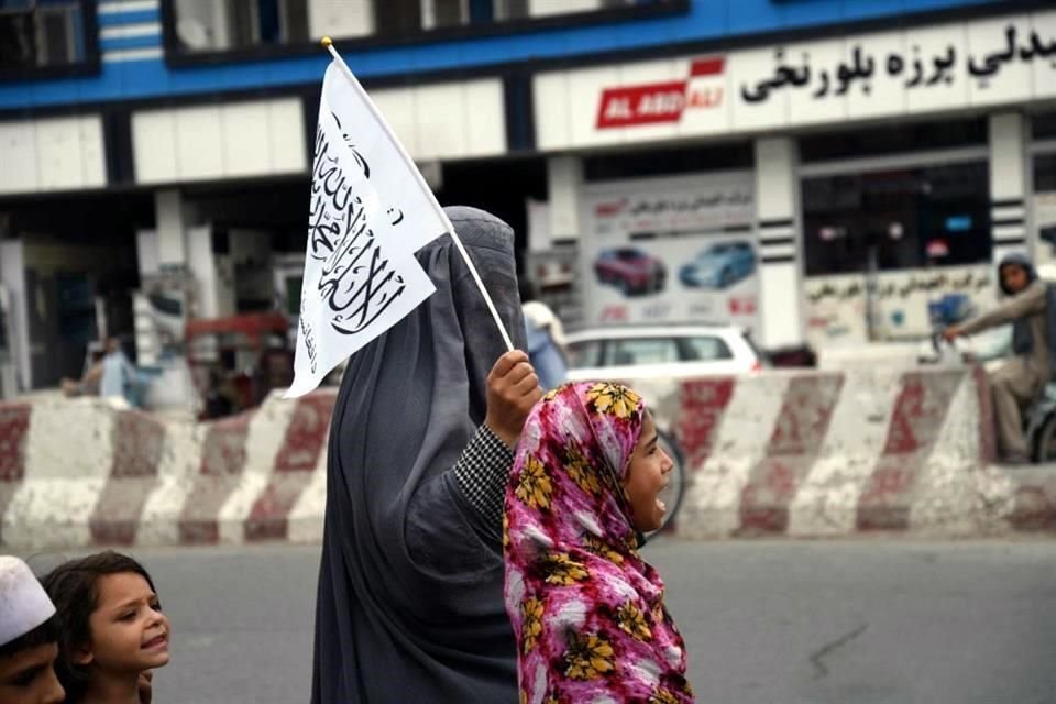 Mujeres y niñas afganas caminan con banderas en las calles de Kandahar para celebrar el aniversario de la victoria talibán.