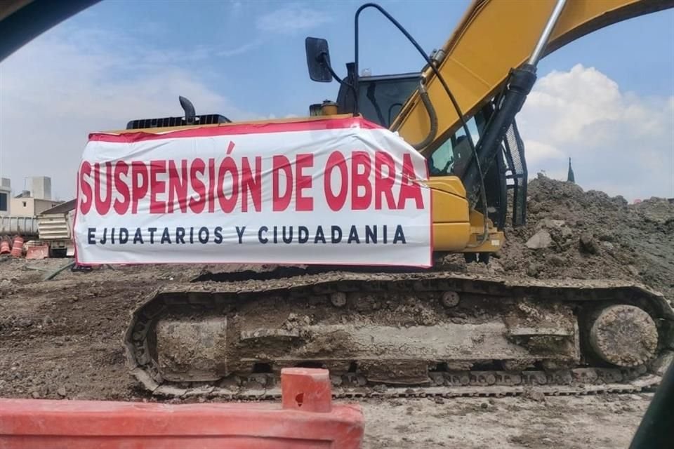 Una grúa de construcción permanece estacionada con un letrero que indica la suspensión de los trabajos por parte de la ciudadanía.