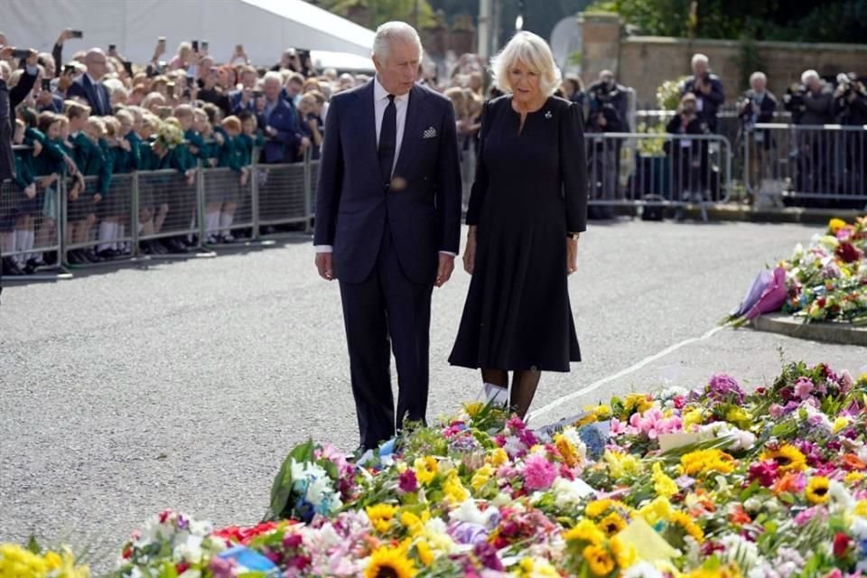 El Rey Carlos y la Reina Camila miran los arreglos florales que la gente dejó en las afueras de la residencia real en Belfast.