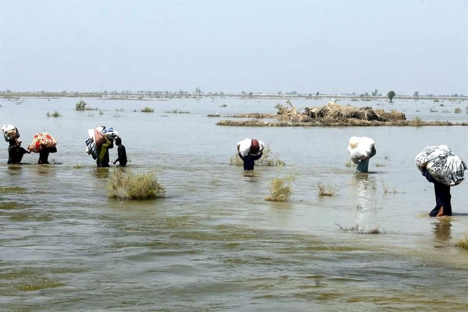 Víctimas de las inundaciones en Pakistán trasladan sus pertenencias.