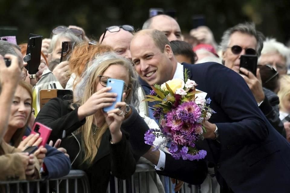 El Príncipe de Gales posa para una foto con un simpatizante mientras veía los tributos florales dejados en memoria de la difunta Reina Isabel II, en Sandringham Estate.