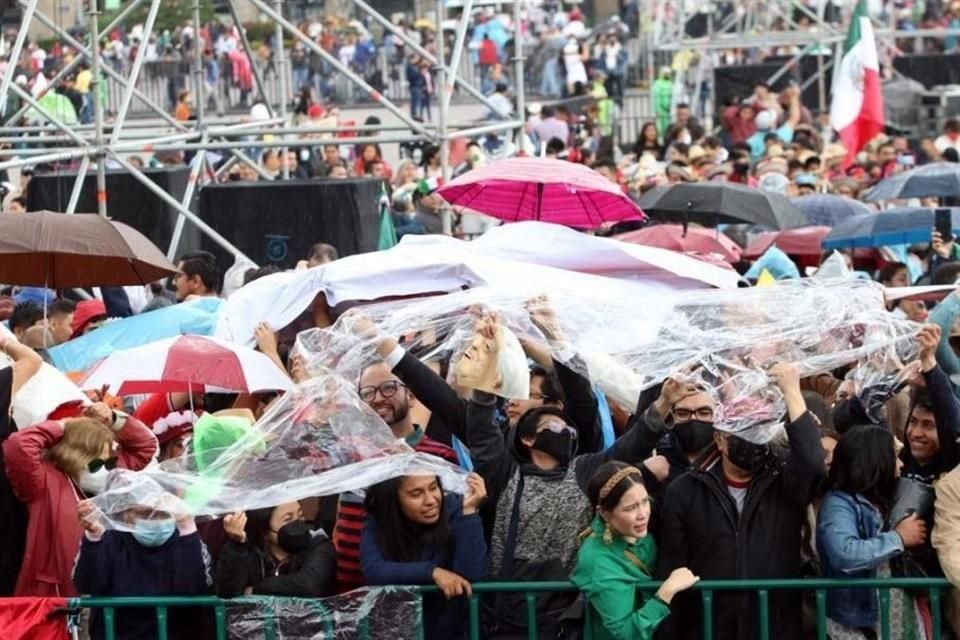 Con pedazos de plástico los pobladores buscan resguardarse de la ligera lluvia que cae en Zócalo de la CDMX.