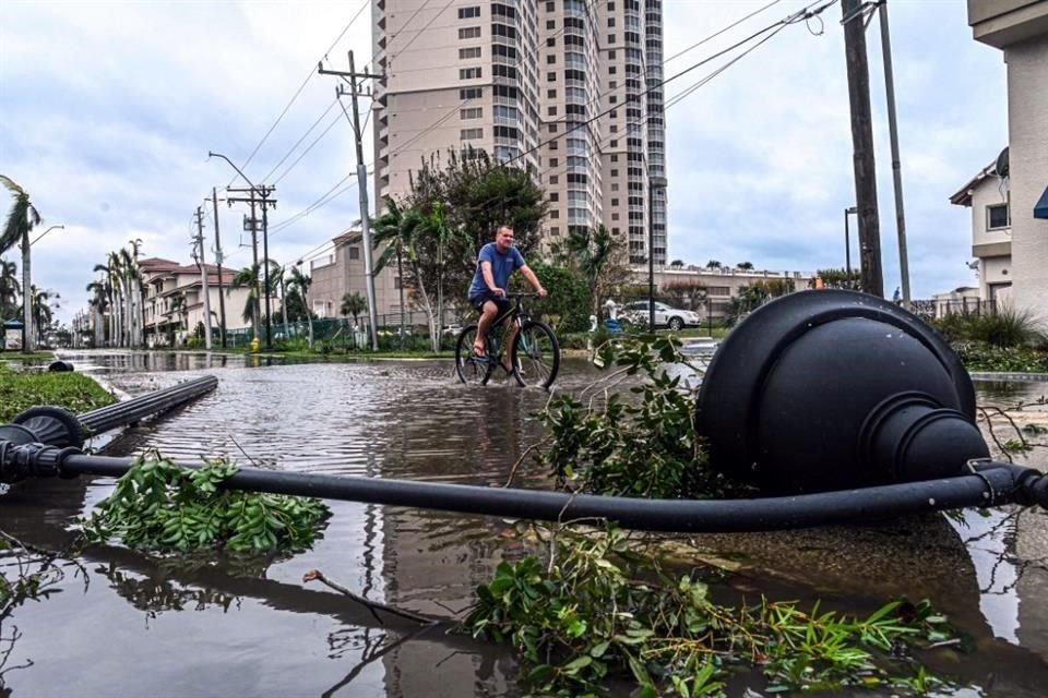 Un hombre recorres las calles con su bicicleta, en medio de los daños por el huracán, en Fort Myers, Florida.