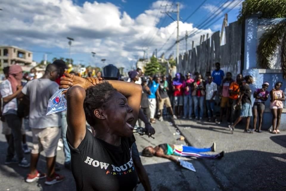 Una mujer llora cerca del cuerpo de otra mujer baleada fatalmente por la policía durante una protesta que exigía la renuncia del Primer Ministro Ariel Henry.