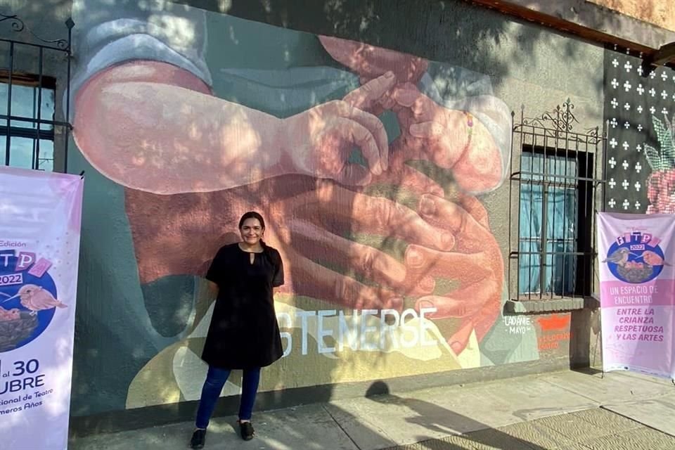 Susana Romo, directora del FITPA, con el mural de Daniela Mayorga 'SosTenerse', dedicado a los bebés, niñas y niños que viven en Puente Grande junto a sus mamás privadas de la libertad.