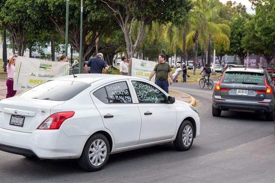 De manera simultánea los coches daban vueltas a la glorieta, al tiempo que otro grupo de vecinos se apostaba con un par de lonas.