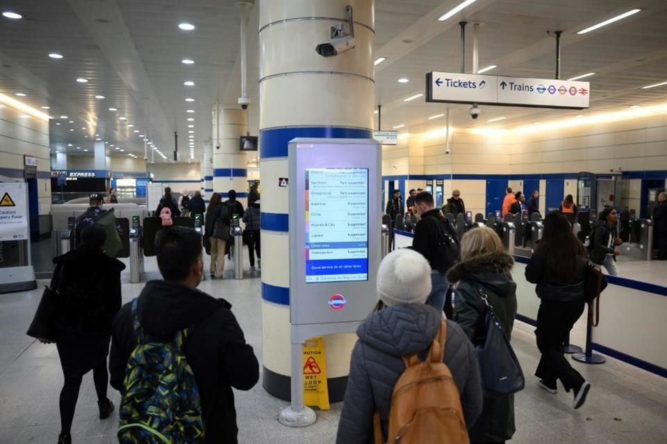 Pasajeros caminan en la estación de Stratford de Londres junto a una anuncio sobre las interrupciones de servicio.