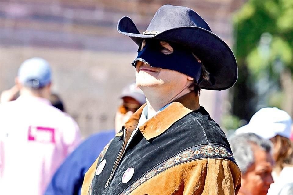 Un hombre participó en la marcha con sombrero y antifaz.