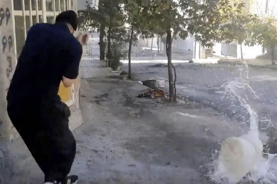 un manifestante reacciona después de que una bala alcanzara un contenedor de agua durante una protesta en Javanroud, una ciudad al oeste de Irán.