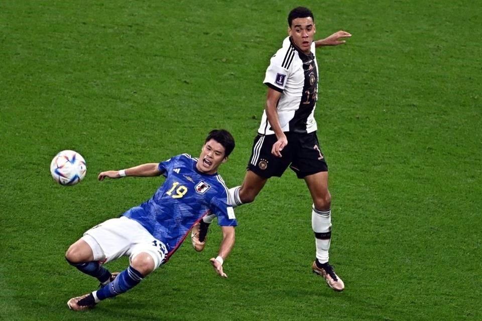 Hiroki Sakai (izq.) y Jamal Musiala disputan el balón en la mitad de la cancha.