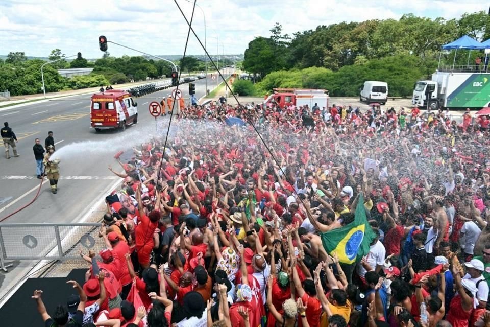 Bomberos rocían agua para aliviar del calor a los partidarios del presidente electo mientras se reúnen para esperar su ceremonia de toma de posesión.