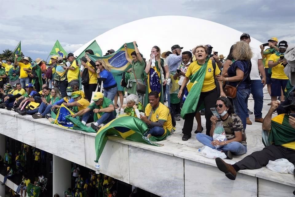 Los manifestantes, partidarios del expresidente de Brasil, Jair Bolsonaro, se paran en el techo del edificio del Congreso Nacional después de que lo asaltaron.