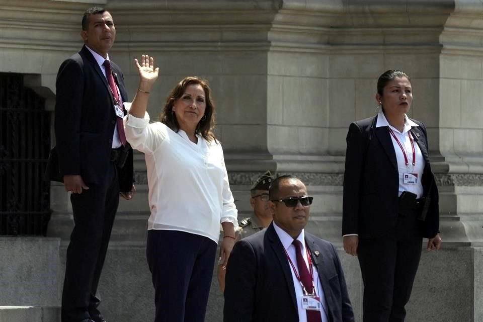 Rodeada de agentes de seguridad, la presidenta de Perú, Dina Boluarte, saluda a la prensa en el exterior del palacio presidencial.