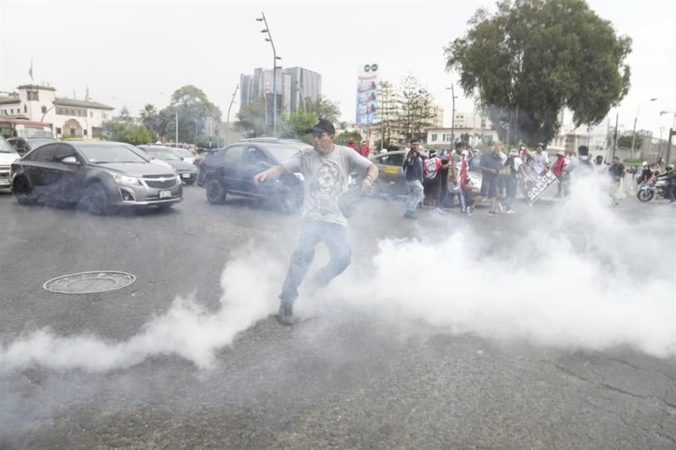 Un manifestante arroja de vuelta una lata de gas lacrimógeno que lanzó la Policía.