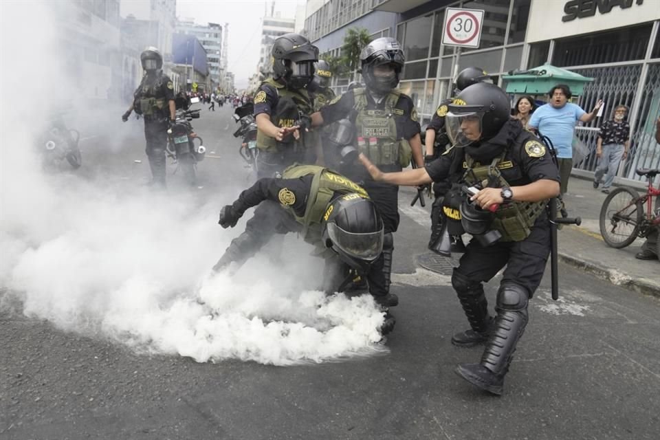 Policías recogen una lata de gas lacrimógeno que les fue lanzada de vuelta por manifestantes.