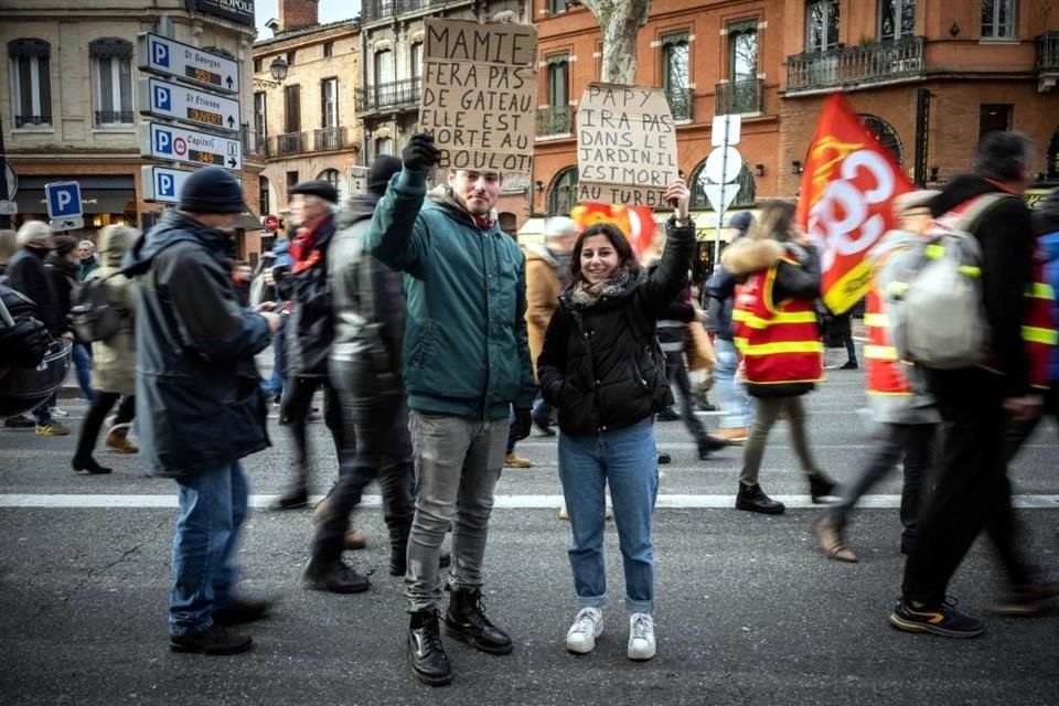 Guillaume y Sarah, estudiantes de 26 y 25 años, sostienen pancartas durante una manifestación.