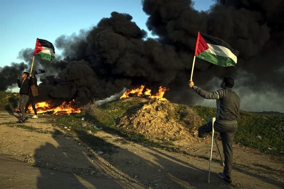 Los palestinos queman neumáticos y ondean la bandera nacional durante una protesta contra el ataque militar israelí en la ciudad de Jenin, en Cisjordania.