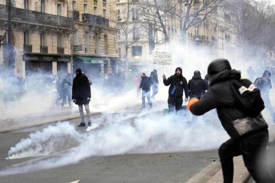 Los manifestantes se paran en medio de gases lacrimógenos durante un incidente.