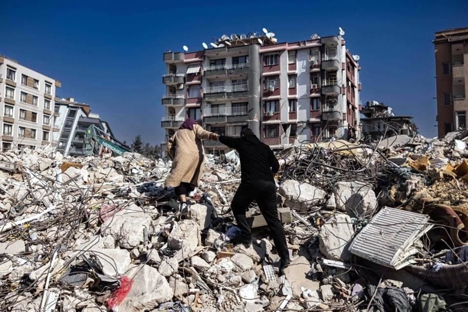 Una pareja escala los escombros de los edificios derrumbados en Antakya, al sur de Turquía.