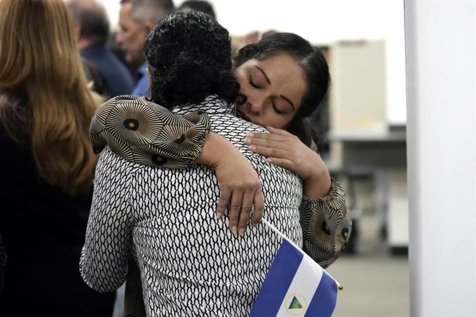 María José Aragón sostiene una bandera nicaragüense mientras abraza a María José Martínez, ambas prisioneras políticas recientemente liberadas de Nicaragua.