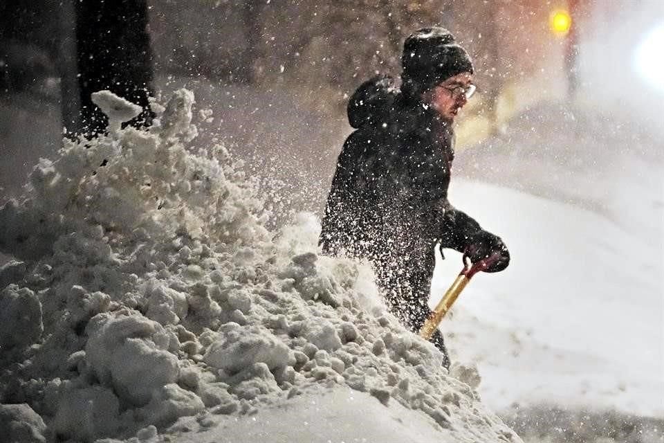 Un hombre limpia la nieve del callejón para tratar de pasar su automóvil a través de un banco de nieve.