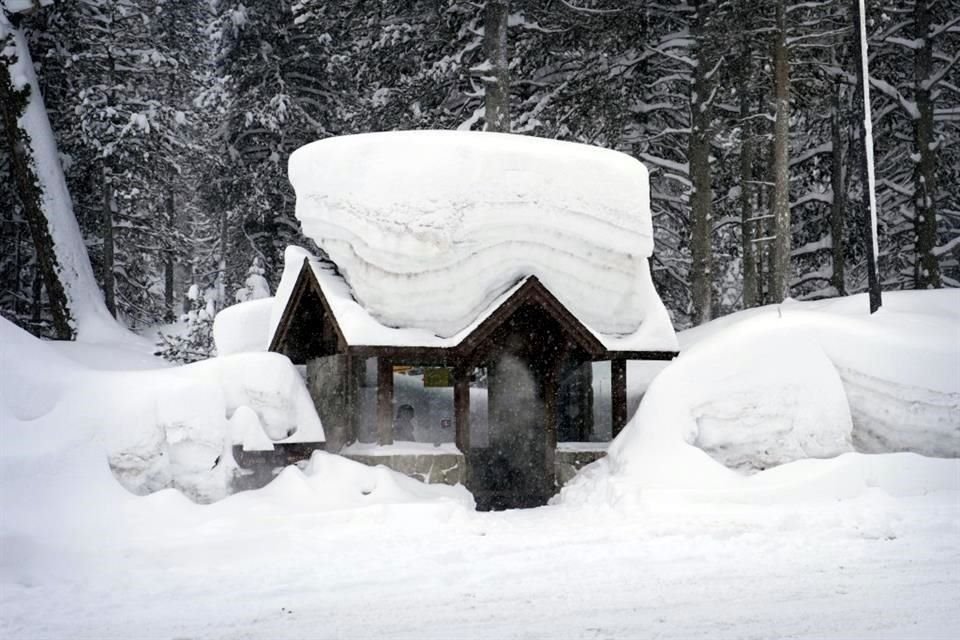 Una persona permanece en una parada de autobús cubierta por la nieve.