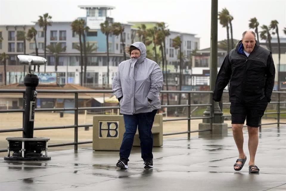 Personas caminan por el muelle de Huntington Beach, California.